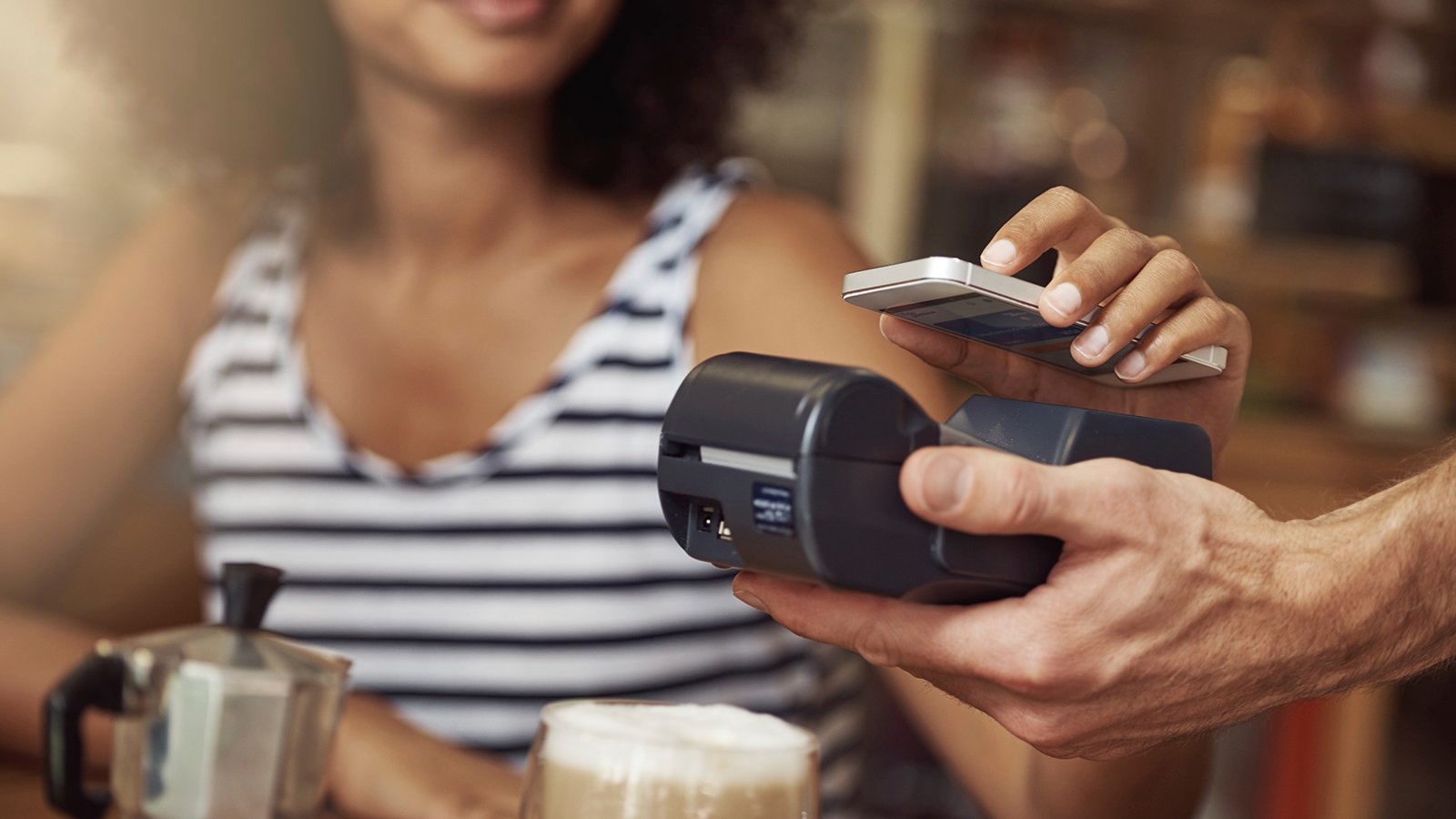 A female individual is seen holding a phone and a credit card, utilizing a cashless payment method. 