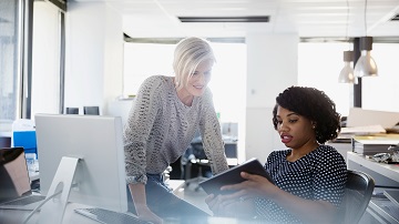 visa-digital-solutions-crosslink-360x202 Two women at a desk looking at a tablet and discussing content on it.