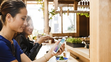visa-ready-crosslink-360x202 Two women looking at mobile phone while at lunch.