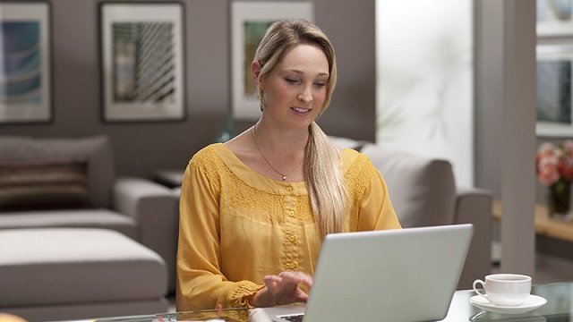 Woman using laptop with cup of coffee nearby. Woman using laptop with cup of coffee nearby.