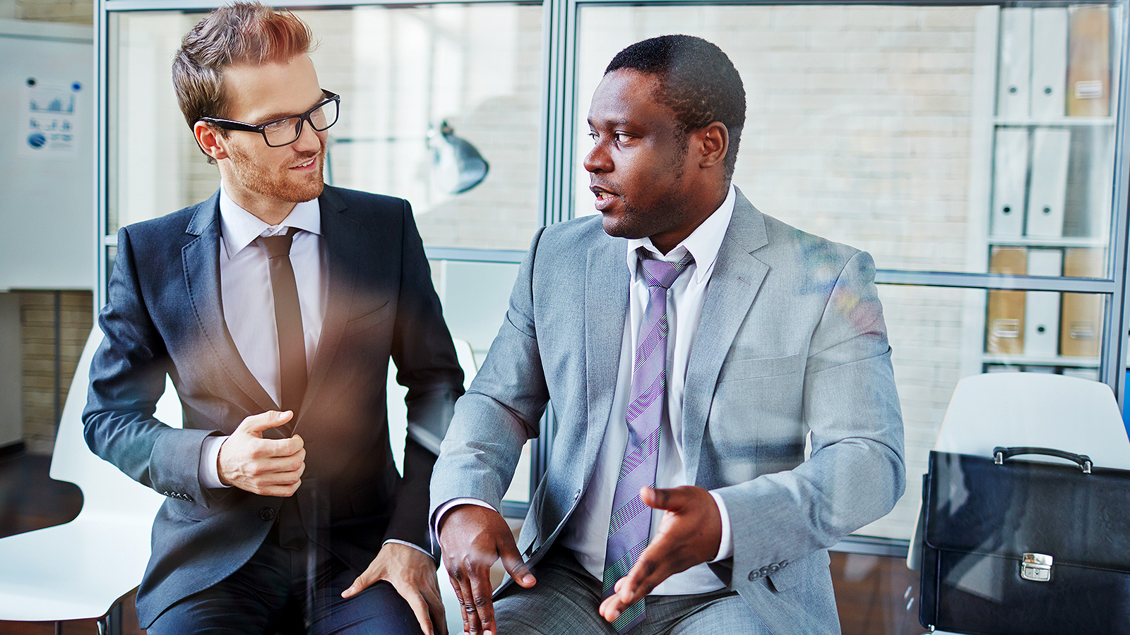 Two businessmen sitting side-by-side engaged in a discussion.