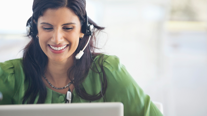 Woman wearing a headset using a laptop.